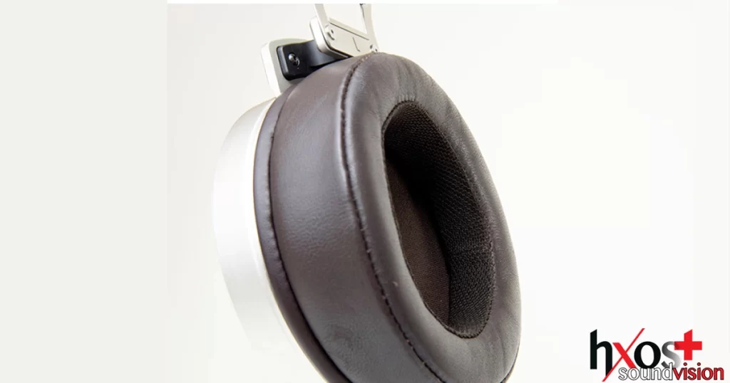 Ηλεκτροστατικά ακουστικά Stax SR-007S με δερμάτινα μαξιλαράκια, vintage σχεδίαση και μεταλλική γέφυρα κεφαλής, τοποθετημένα σε ξύλινη βάση.