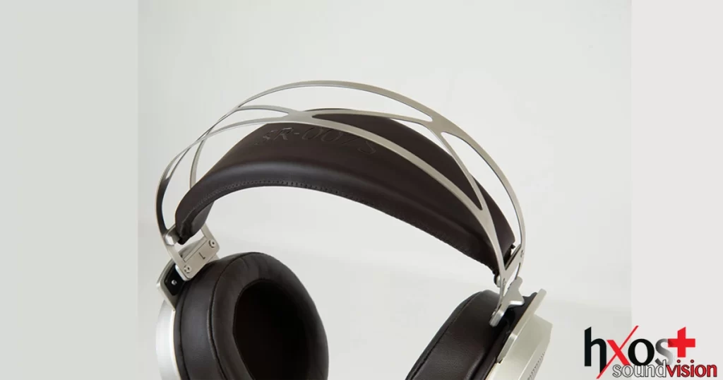 Ηλεκτροστατικά ακουστικά Stax SR-007S με δερμάτινα μαξιλαράκια, vintage σχεδίαση και μεταλλική γέφυρα κεφαλής, τοποθετημένα σε ξύλινη βάση.